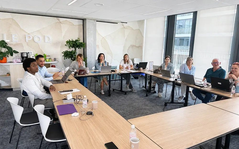 Des participants suivent une session devant leur ordinateur portable, en salle